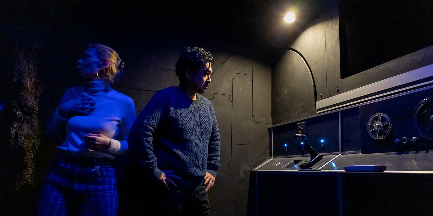 A man and woman experiencing the excitement of "For Queen and Country" escape room.
